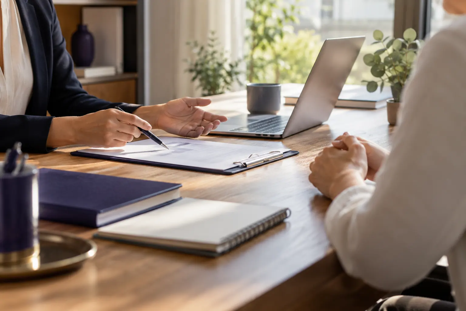 Professionnelle libérale commentant un document sur porte-bloc face à un client, autour d'une table en bois lumineuse